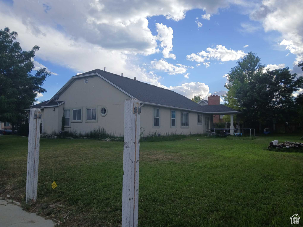View of property exterior with a yard, a chimney, and stucco siding