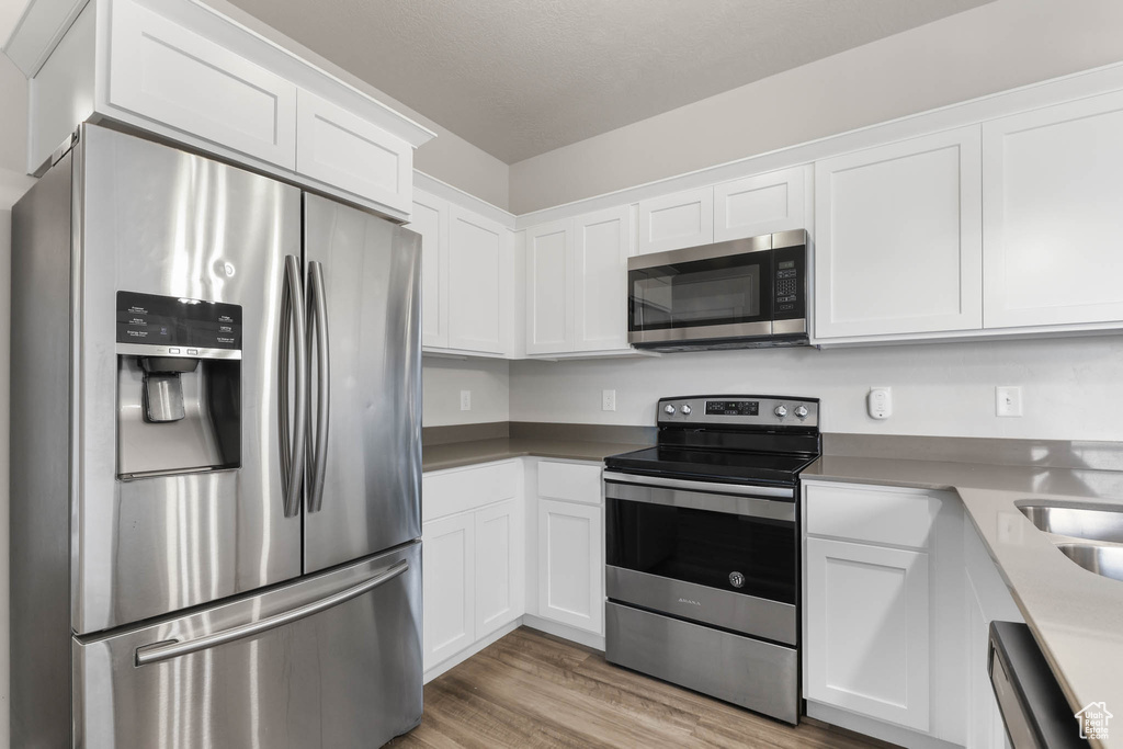 Kitchen featuring appliances with stainless steel finishes, white cabinetry, and light wood-type flooring