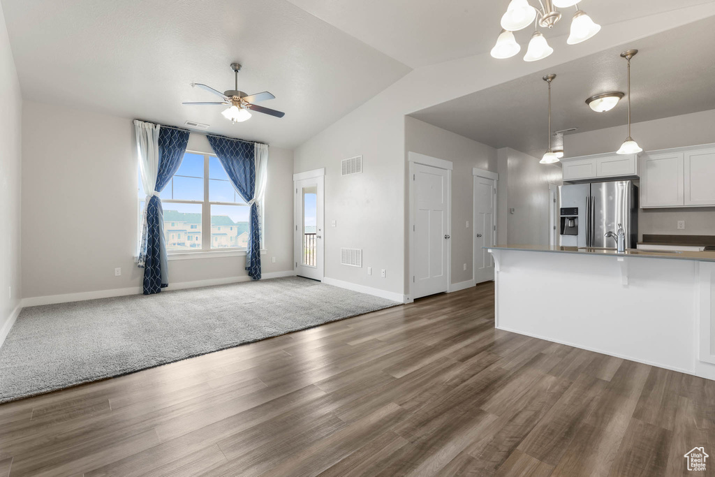 Kitchen with stainless steel fridge with ice dispenser, open floor plan, ceiling fan, lofted ceiling, and wood finished floors