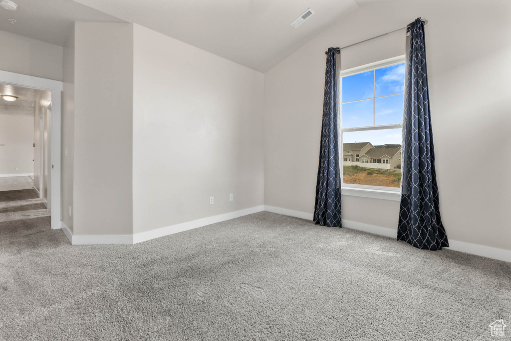 Spare room featuring carpet flooring and lofted ceiling