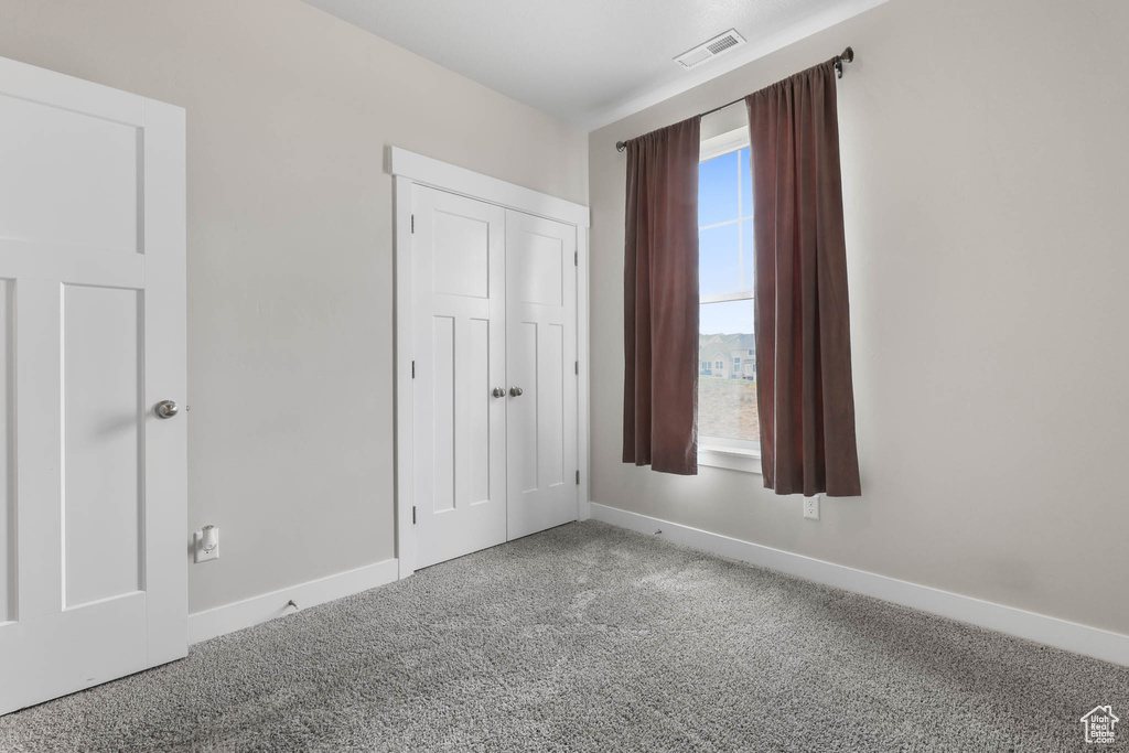 Unfurnished bedroom featuring carpet and a closet