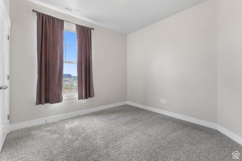 Carpeted spare room featuring baseboards