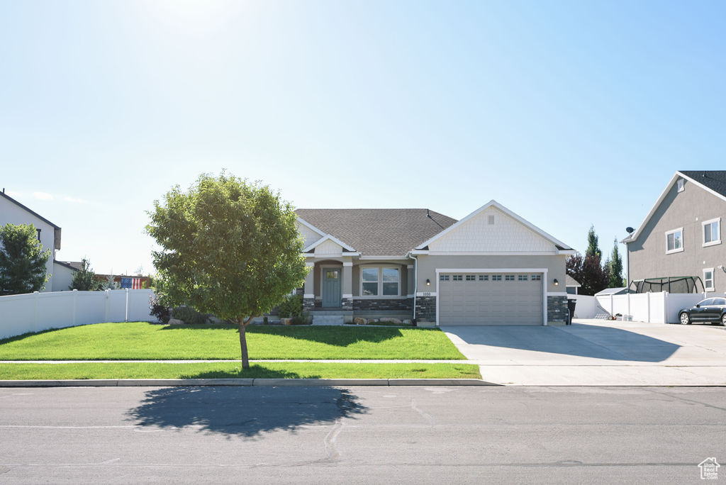 View of front facade with a garage, driveway, and stone siding