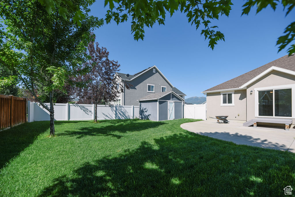 Fenced backyard featuring a storage unit and a patio
