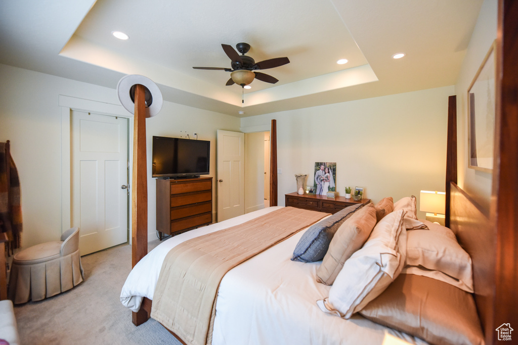 Carpeted bedroom with a tray ceiling, recessed lighting, and a ceiling fan