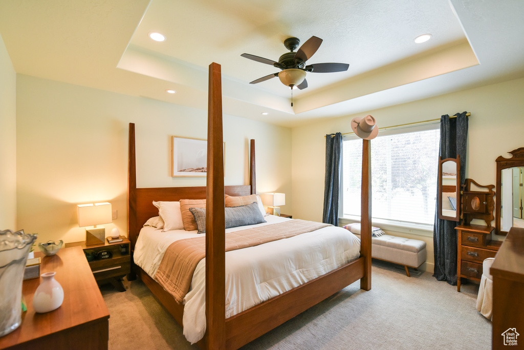 Bedroom featuring a raised ceiling, light carpet, recessed lighting, and a ceiling fan