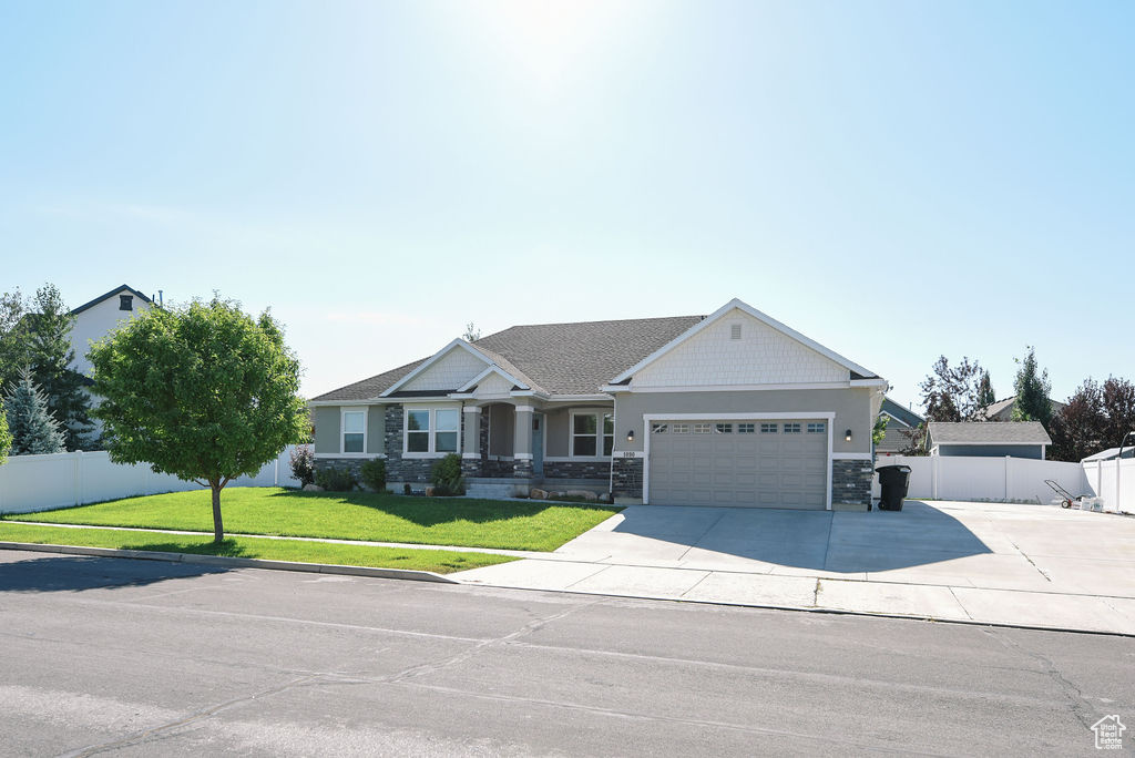 Craftsman-style home with a garage, driveway, and stone siding
