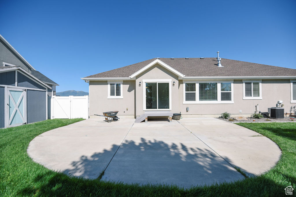 Back of house with stucco siding, a patio area, and a shingled roof