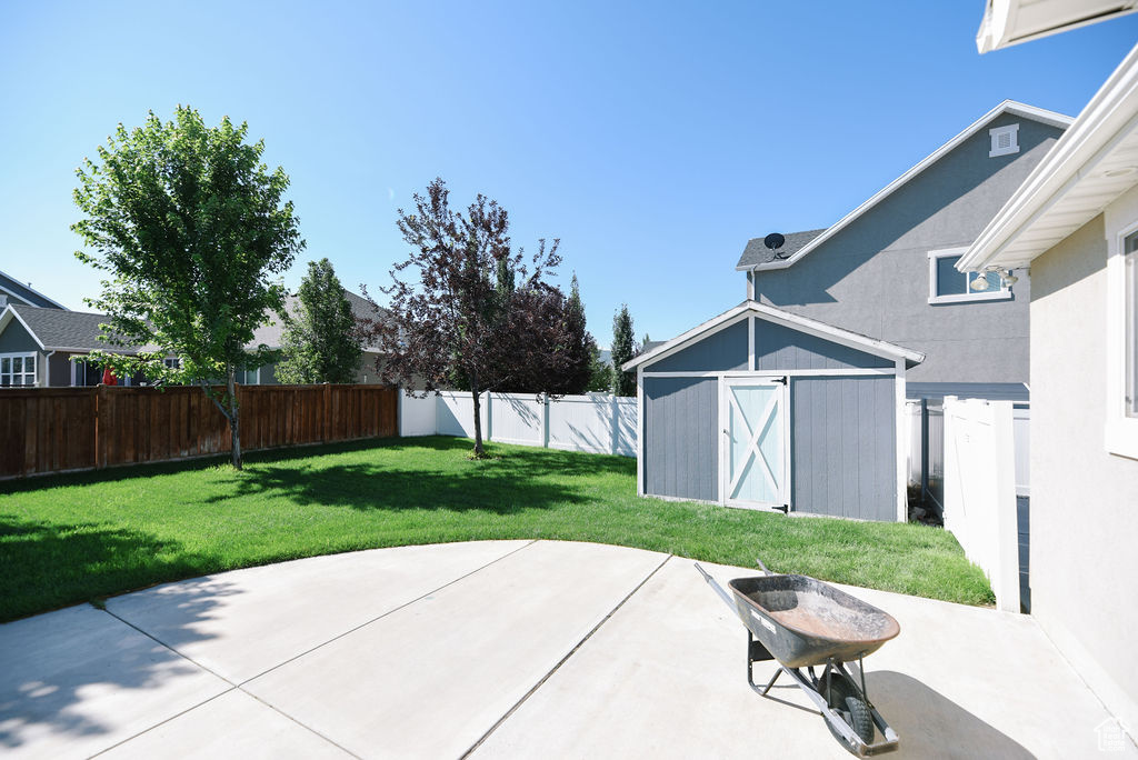 Fenced backyard with a storage shed and a patio area
