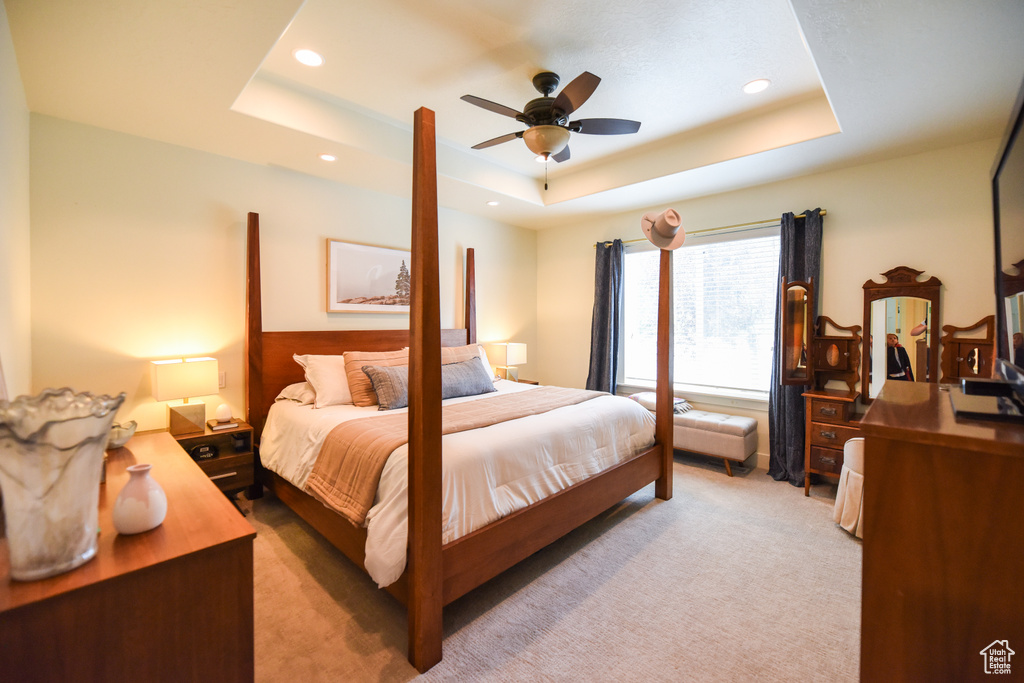 Bedroom with a raised ceiling, light carpet, recessed lighting, and ceiling fan