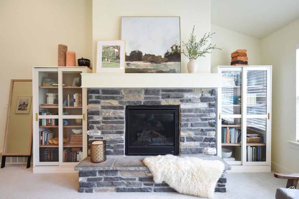 Carpeted living area featuring a fireplace and vaulted ceiling