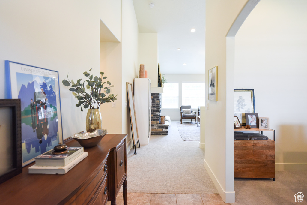 Corridor featuring light colored carpet, arched walkways, recessed lighting, and light tile patterned floors