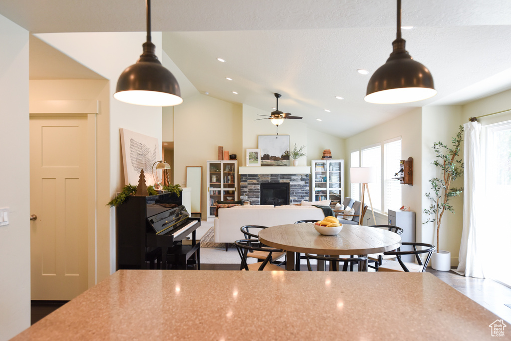 Dining area featuring a fireplace, ceiling fan, vaulted ceiling, and recessed lighting
