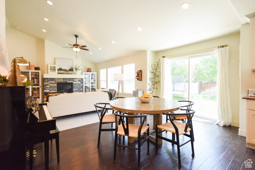Dining space with a fireplace, a ceiling fan, recessed lighting, dark wood-style flooring, and vaulted ceiling