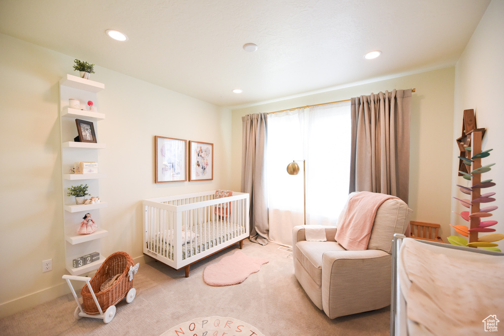 Bedroom with carpet floors, recessed lighting, and a crib