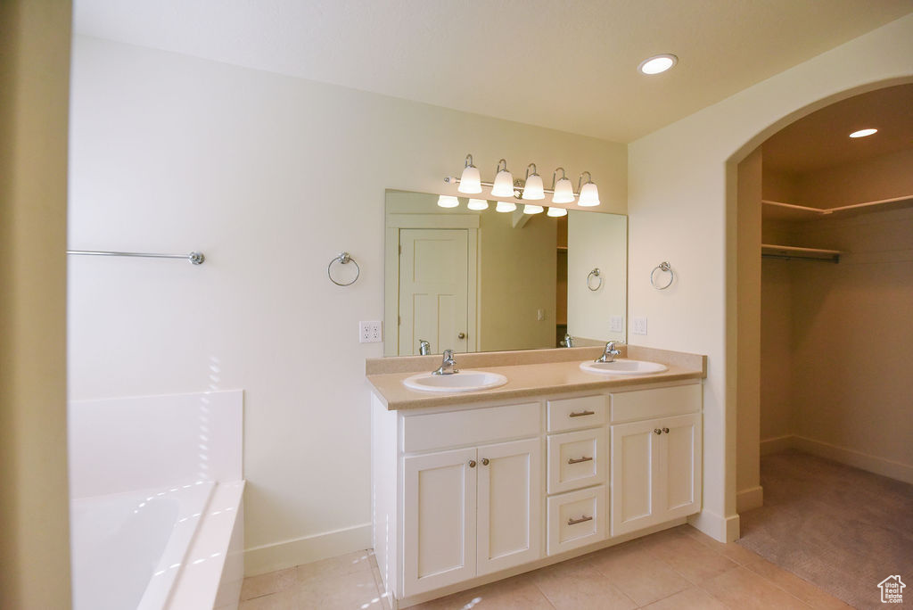 Full bathroom with double vanity, tile patterned flooring, a spacious closet, a garden tub, and recessed lighting