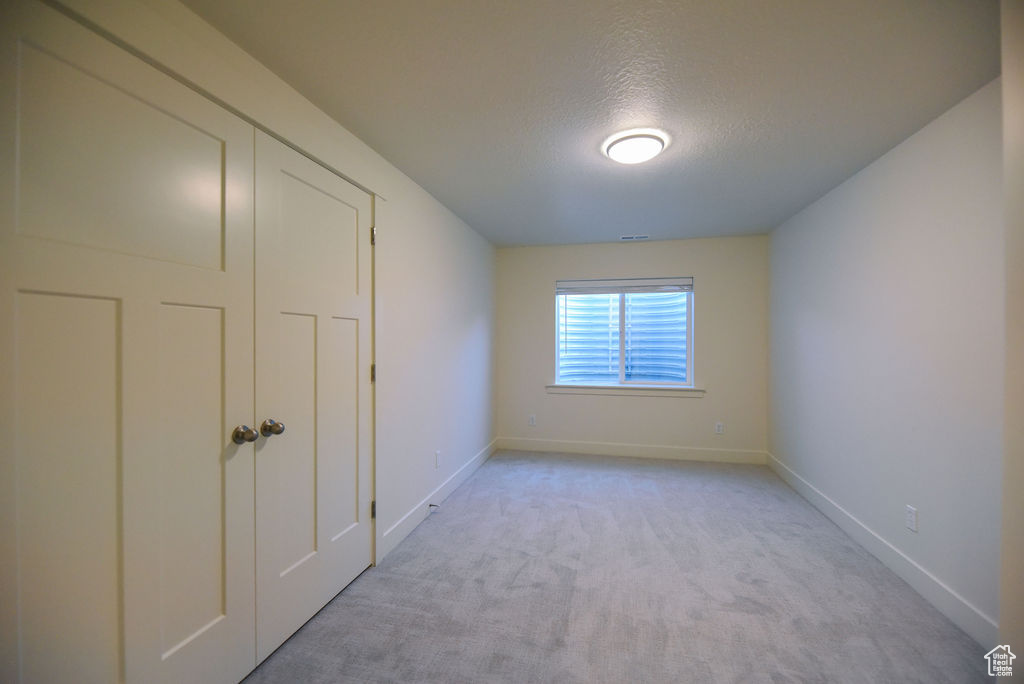 Unfurnished bedroom with a textured ceiling and light colored carpet