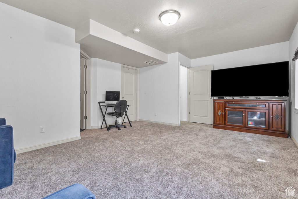 Living room with carpet flooring, a desk, and a textured ceiling