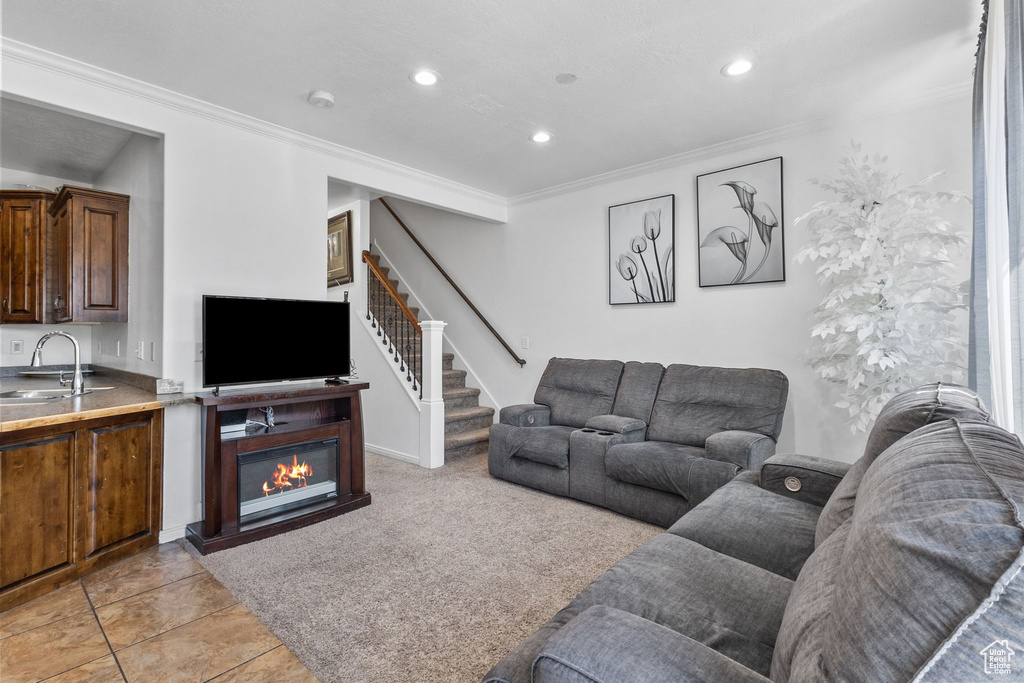 Living area featuring crown molding, stairs, recessed lighting, and a glass covered fireplace