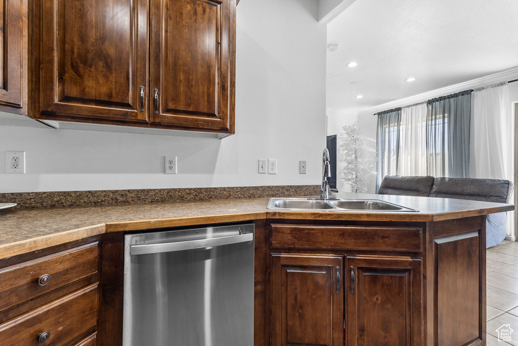 Kitchen featuring stainless steel dishwasher, dark countertops, light tile patterned floors, dark brown cabinets, and recessed lighting