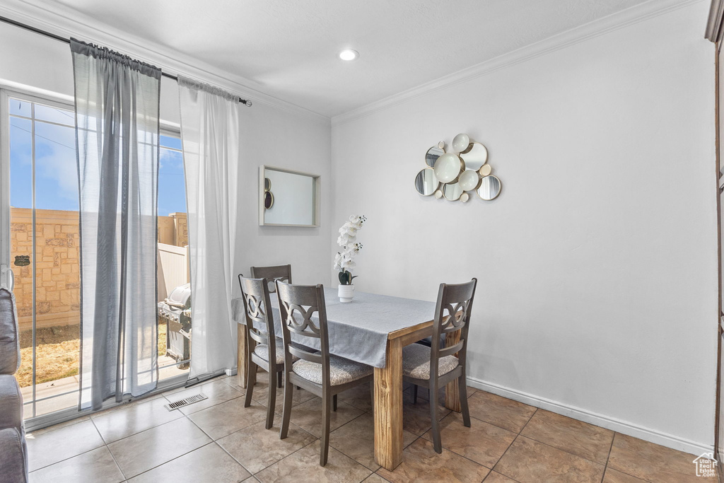 Tiled dining area featuring crown molding and baseboards