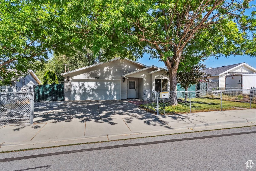 Single story home featuring driveway, a garage, and a fenced front yard