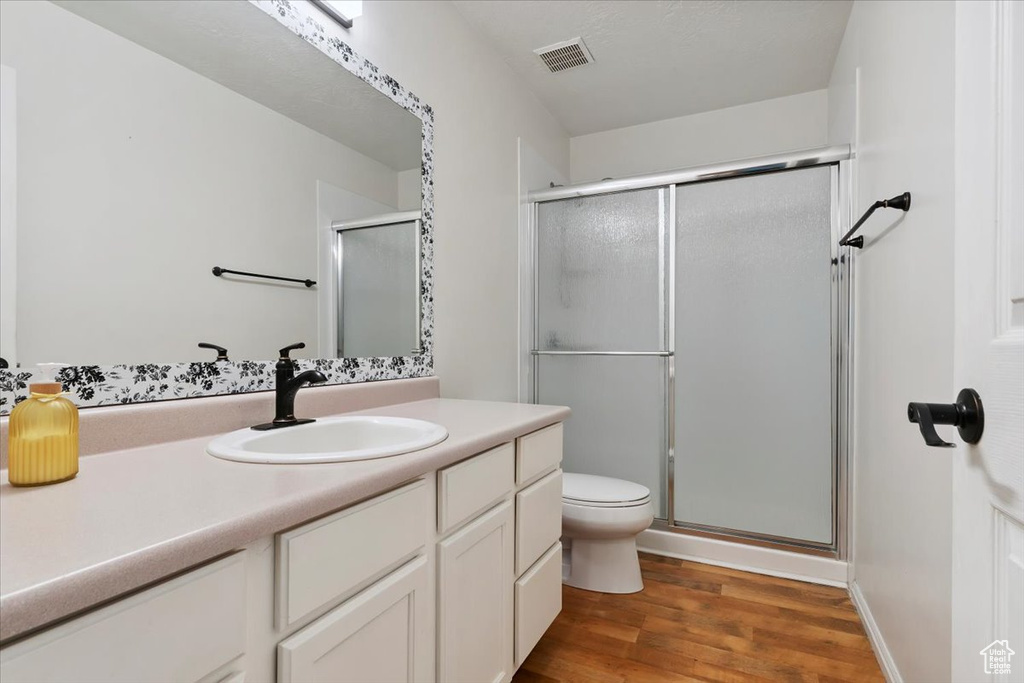 Bathroom featuring wood finished floors, a stall shower, and vanity