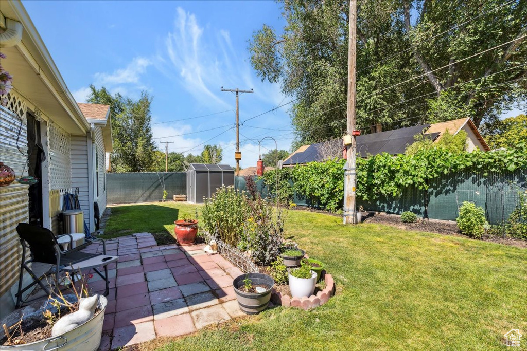 Fenced backyard featuring a shed and a patio area