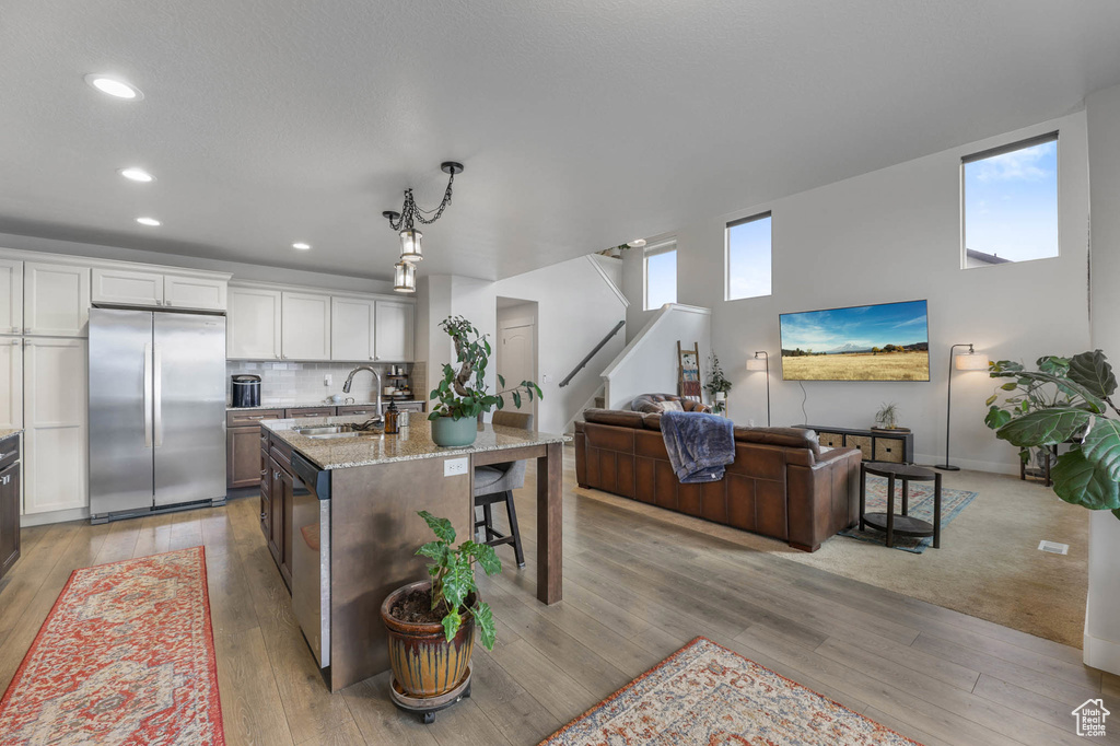 Kitchen with appliances with stainless steel finishes, open floor plan, healthy amount of natural light, light stone countertops, and recessed lighting