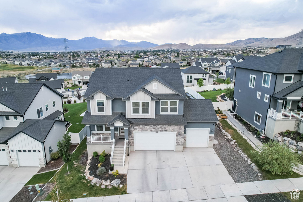 View of front of home with a residential view, driveway, stone siding, and a mountain view