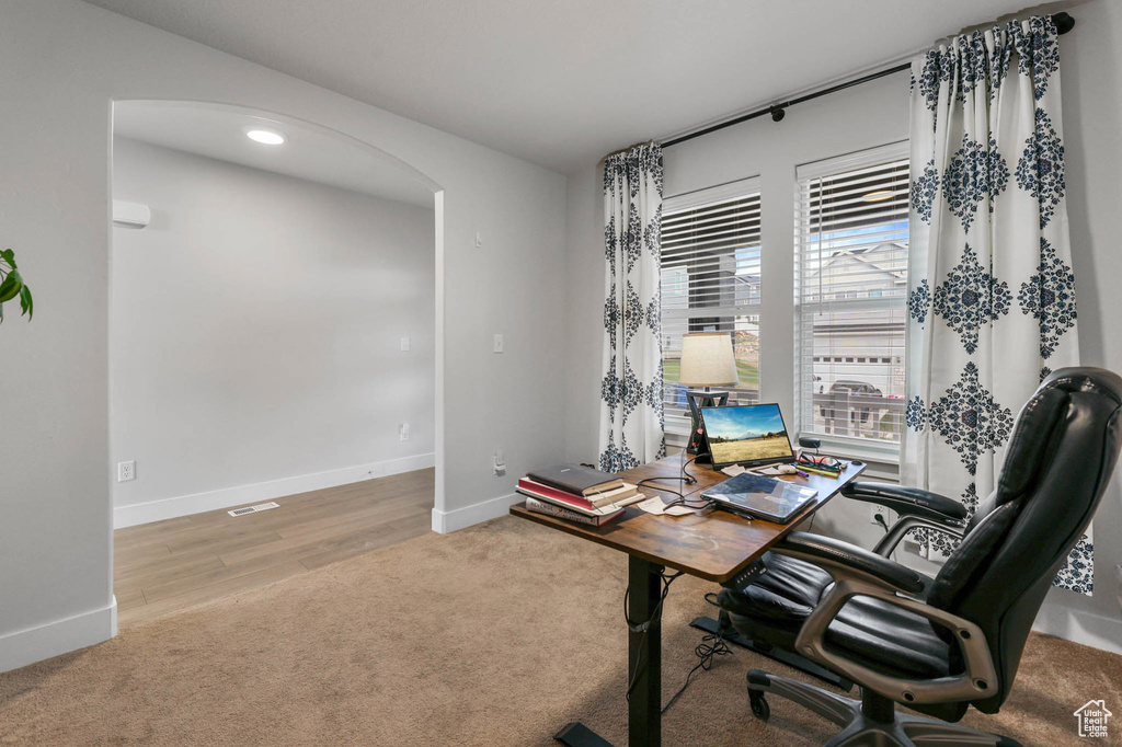 Carpeted office space featuring arched walkways and recessed lighting