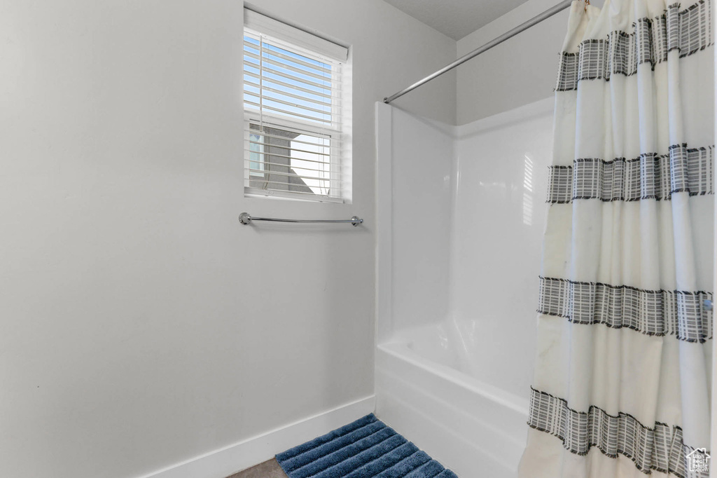 Bathroom featuring baseboards and shower / bath combo with shower curtain