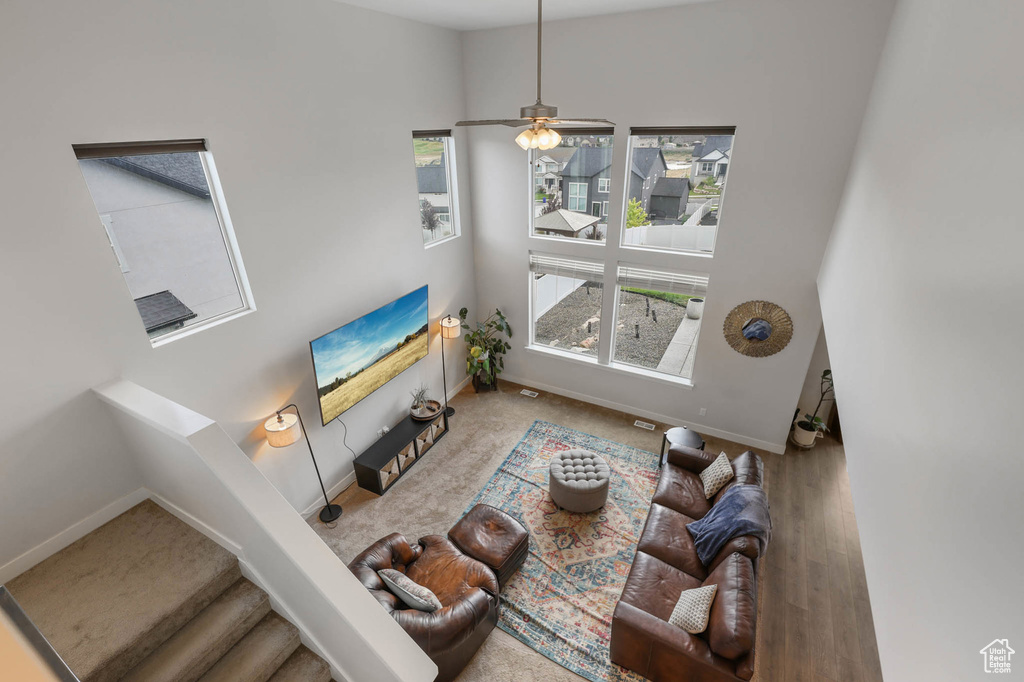 Living area with stairway, a towering ceiling, and ceiling fan