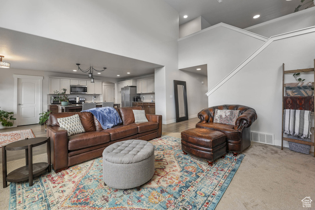 Living area with recessed lighting, light colored carpet, and a high ceiling