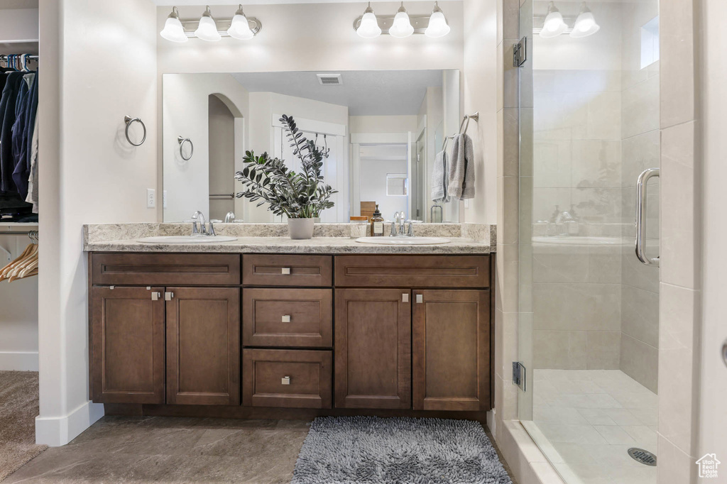 Full bath featuring a stall shower, double vanity, and a walk in closet