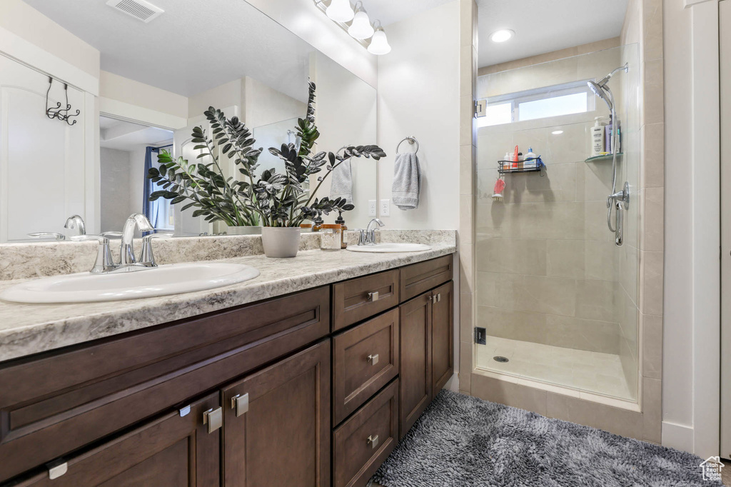 Full bathroom featuring double vanity and a stall shower