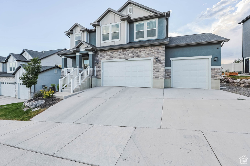 Craftsman house featuring stone siding, board and batten siding, an attached garage, and concrete driveway