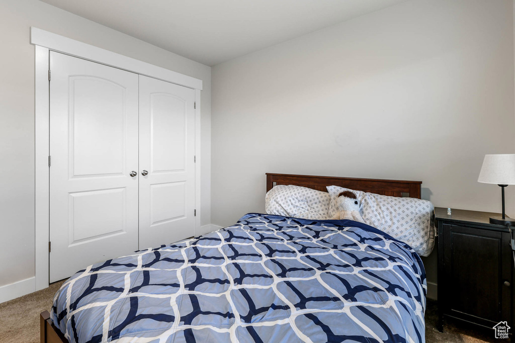 Carpeted bedroom featuring a closet and baseboards