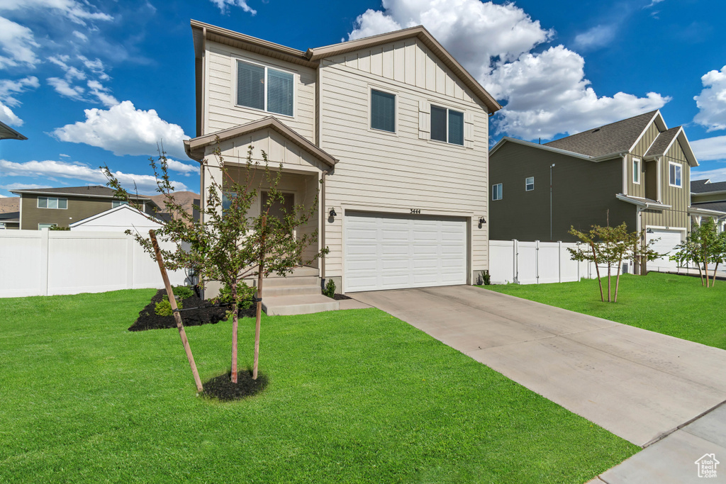 View of front of property with board and batten siding, an attached garage, and concrete driveway