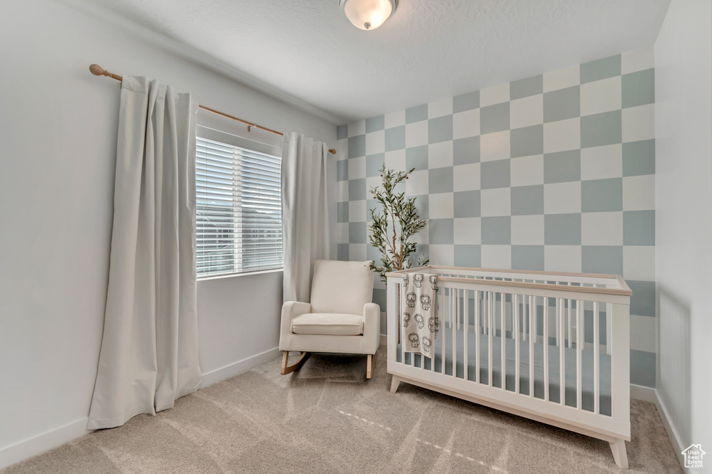 Bedroom featuring carpet flooring and a crib
