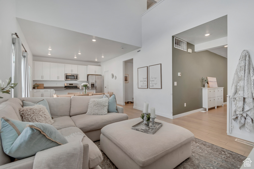 Living room featuring light wood-style flooring, recessed lighting, and a high ceiling