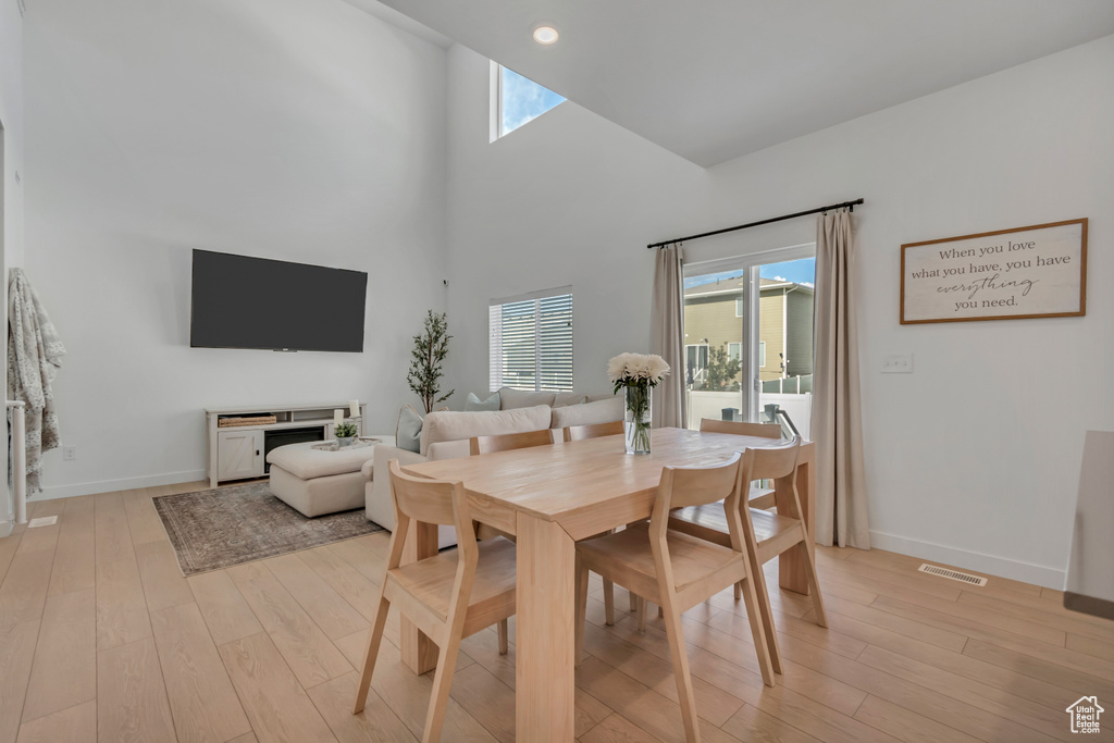 Dining space with light wood-style flooring, healthy amount of natural light, a high ceiling, and recessed lighting