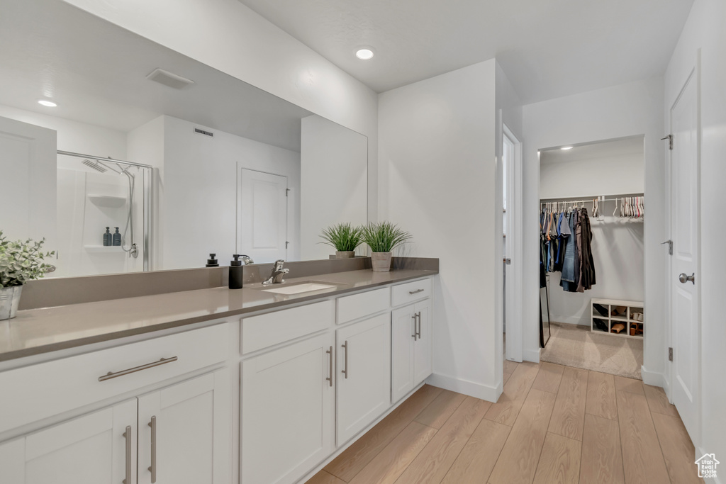 Bathroom with vanity, wood finished floors, a walk in closet, a shower, and recessed lighting