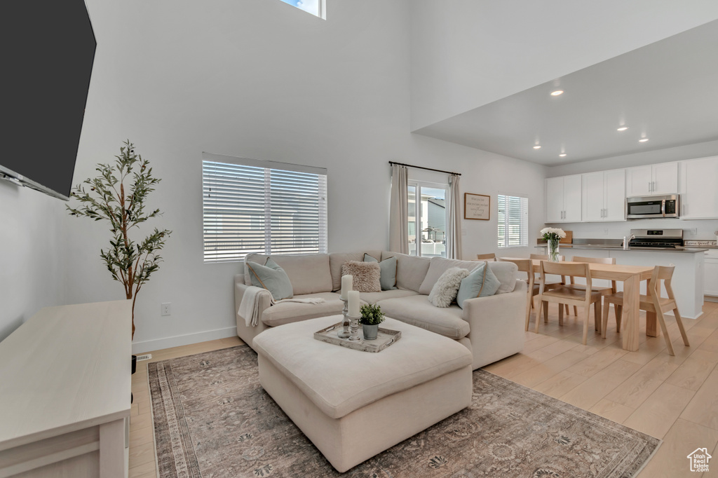 Living room featuring light wood-style floors, recessed lighting, and a high ceiling