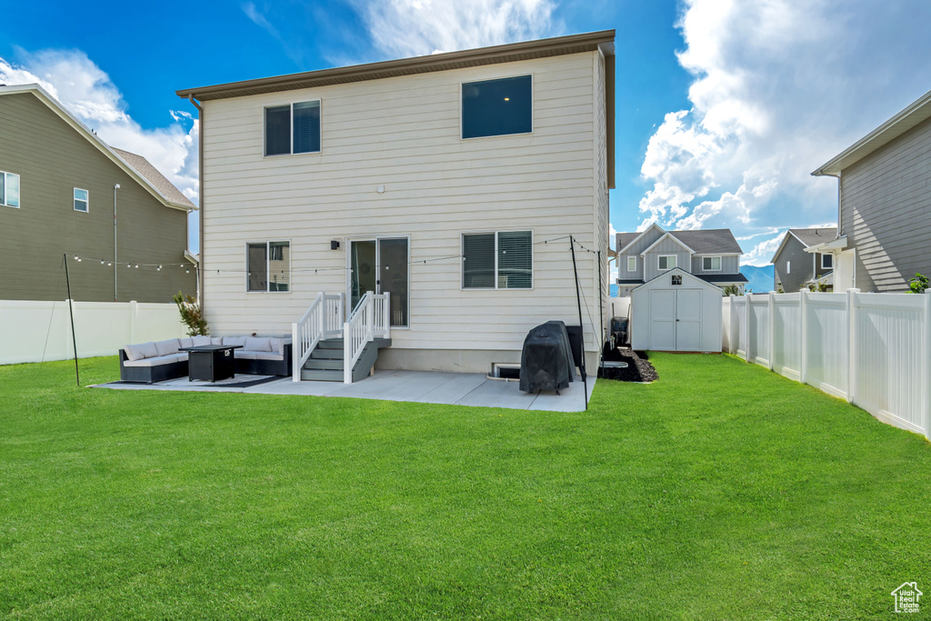 Rear view of property with outdoor lounge area, a patio area, a fenced backyard, and a storage unit