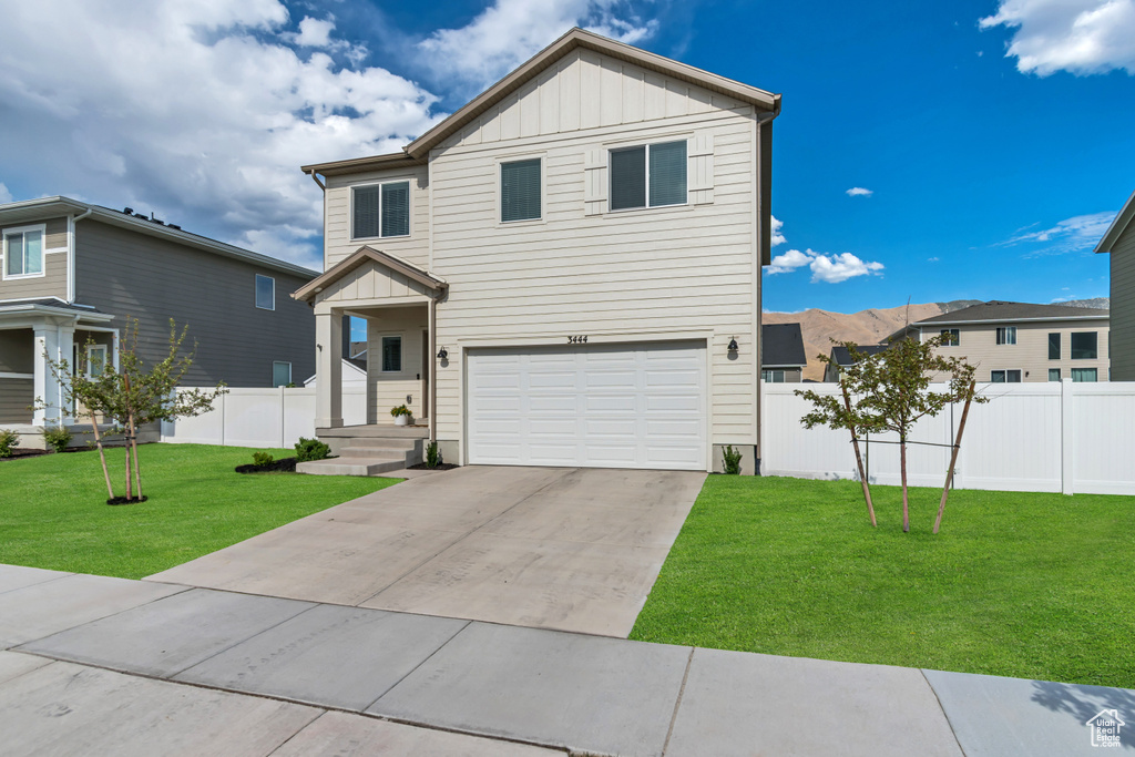 View of front of house with board and batten siding, a garage, and concrete driveway