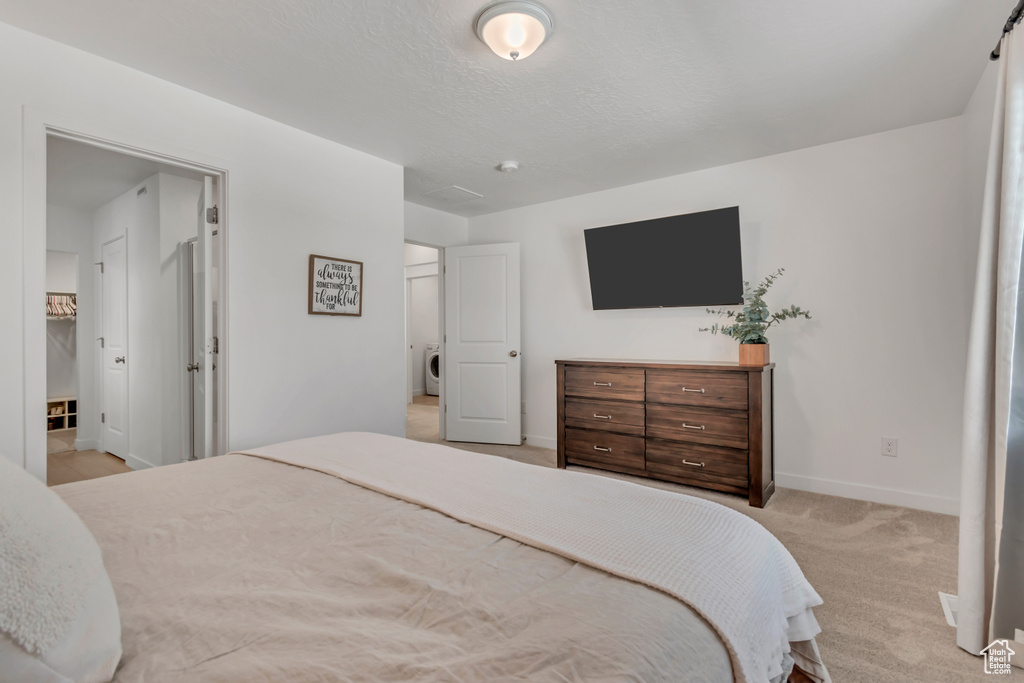 Bedroom featuring light colored carpet and washer / dryer