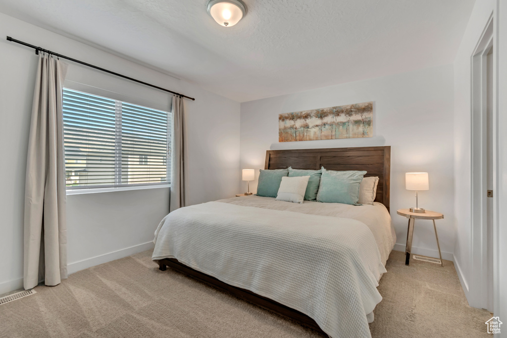 Bedroom with light colored carpet and baseboards