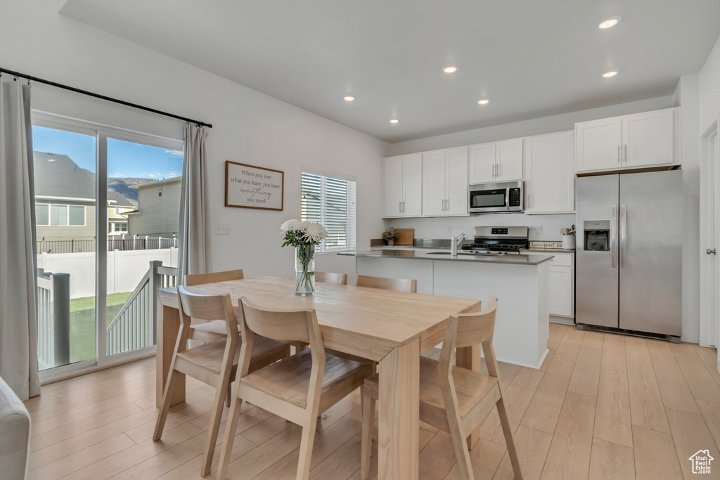 Kitchen featuring appliances with stainless steel finishes, light wood-style flooring, plenty of natural light, white cabinets, and recessed lighting