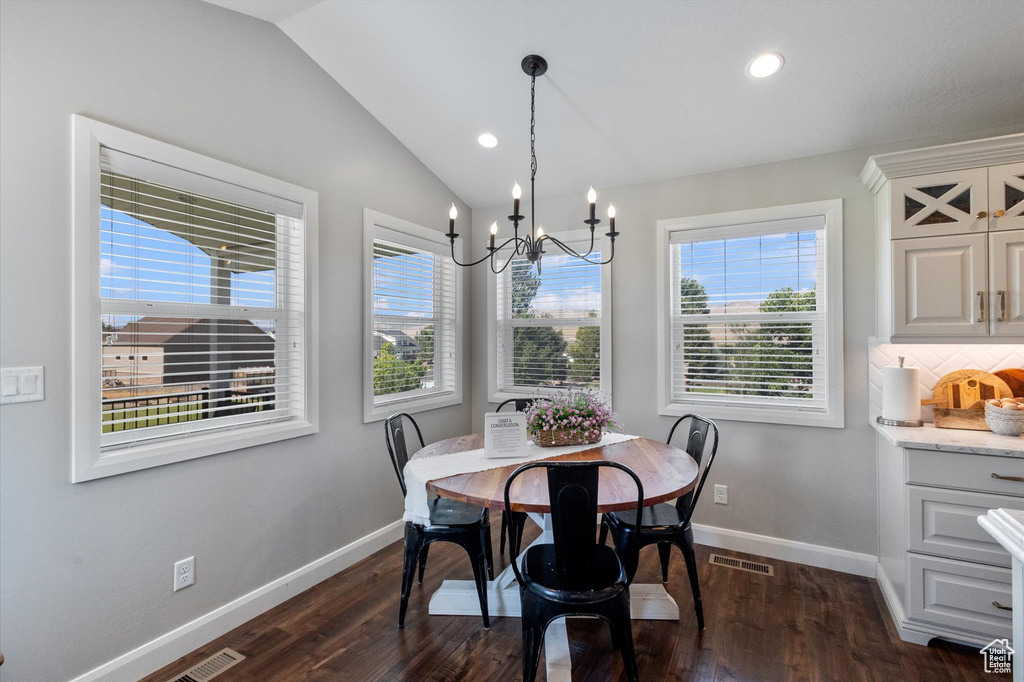 Dining area with vaulted ceiling, plenty of natural light, a chandelier, dark wood-type flooring, and recessed lighting